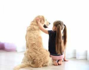 Hund und Mädchen sitzen nebeneinander auf dem Boden