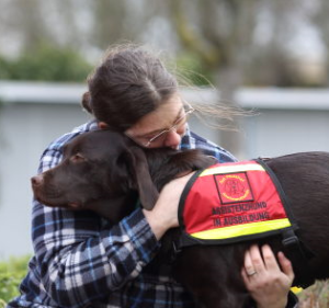 Man hugs an assistance dog