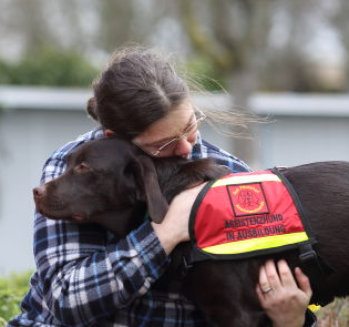 Mensch umarmt einen Assistenzhund